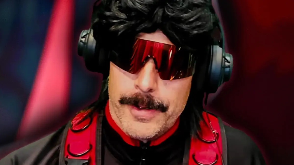 Dr Disrespect, who is wearing red visor glasses, a black wig, and a black and red tactical turtleneck, talks to the camera.