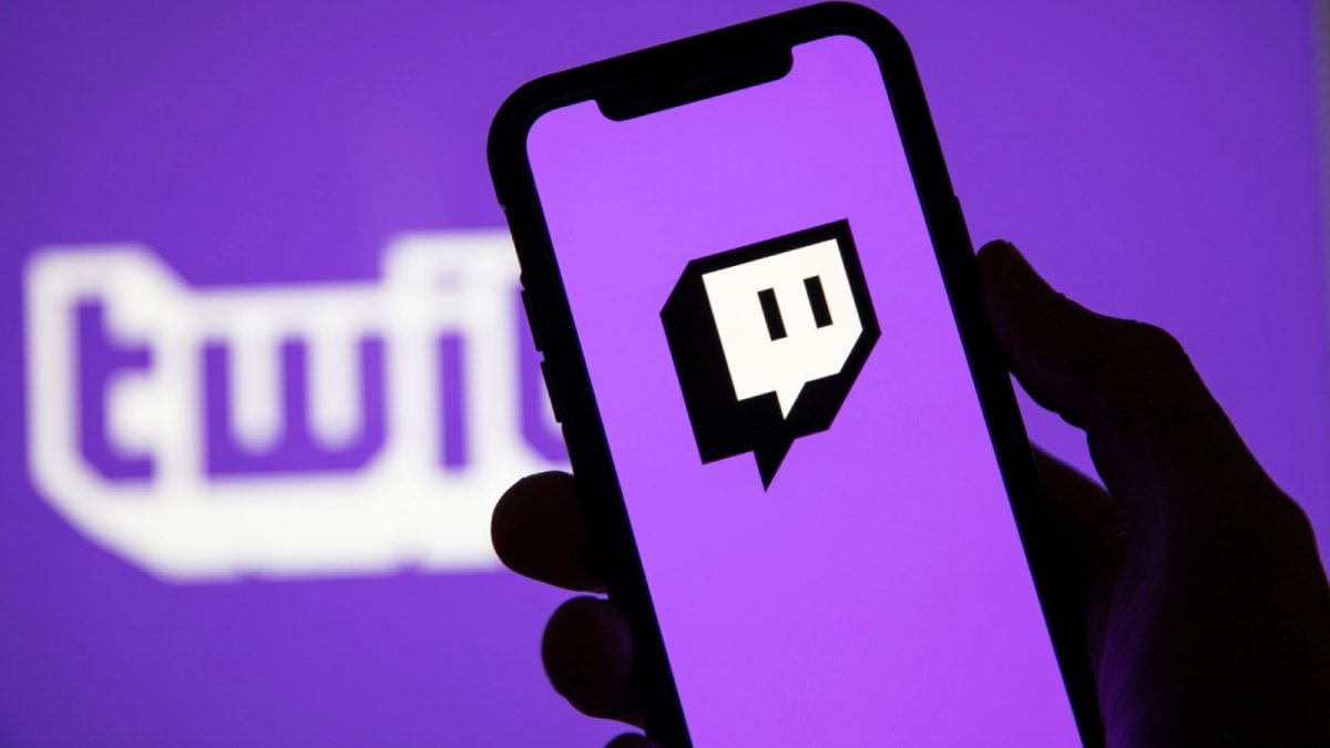 Person holding a phone with the Twitch logo displayed on it.