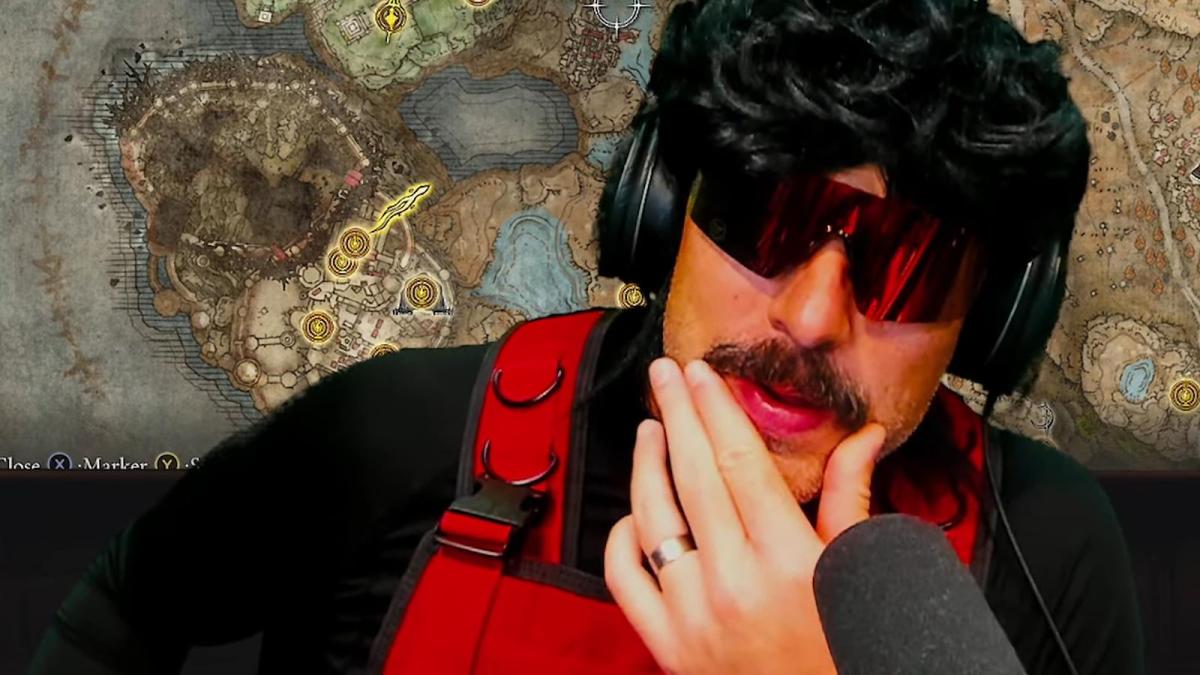 Dr Disrespect, dressed in a red visor with a black wig and his usual red jetsuit, rubs his chin pensively.